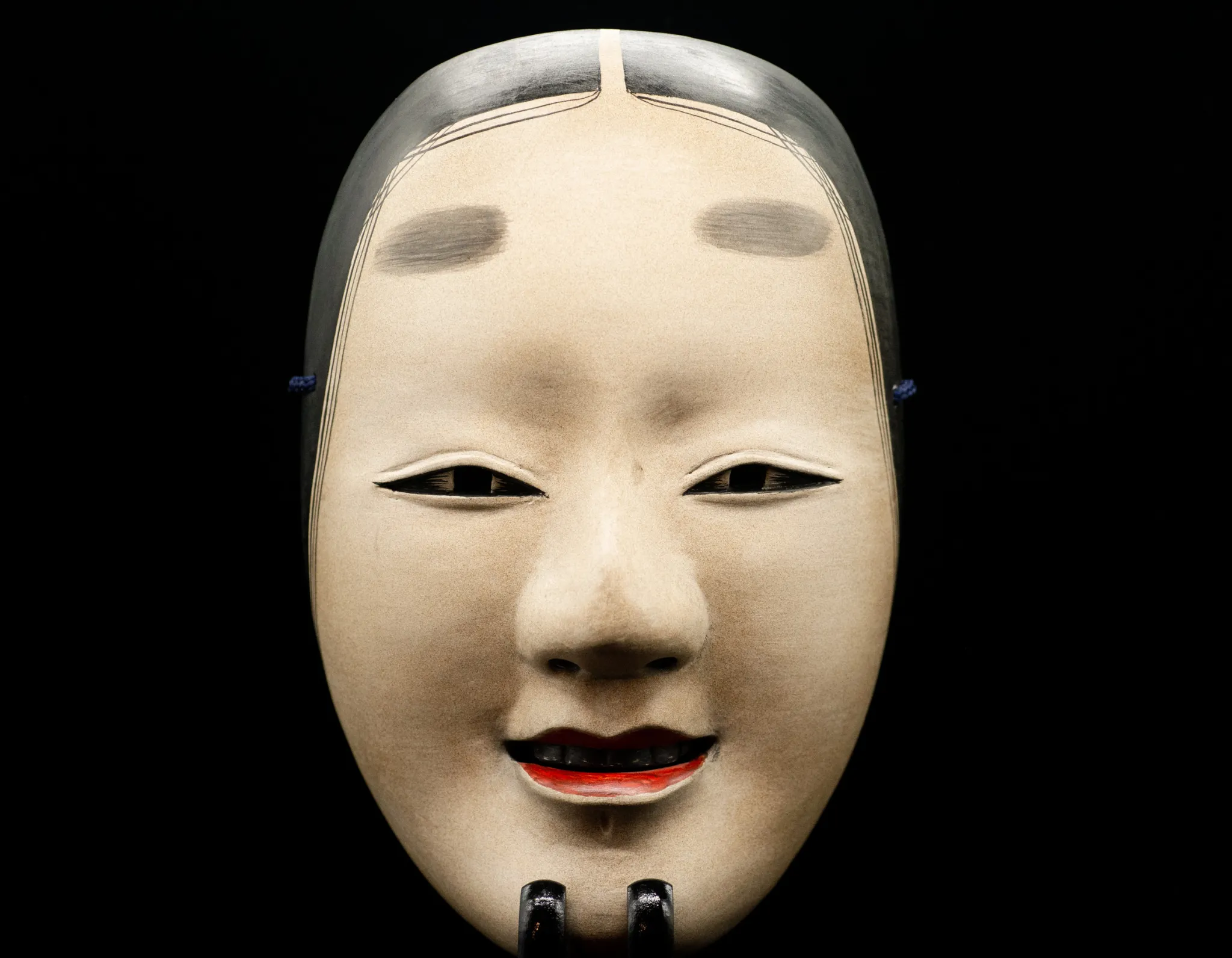 Carved wooden mask from the Noh theatre, Showa period. Signed Seiun 静雲. Representing Ko omote, ‘Ko’ means tenderness, youth and beauty. ‘Omote’ means face. The mask shows the beautiful face of a young woman whose nature is calm and serene.